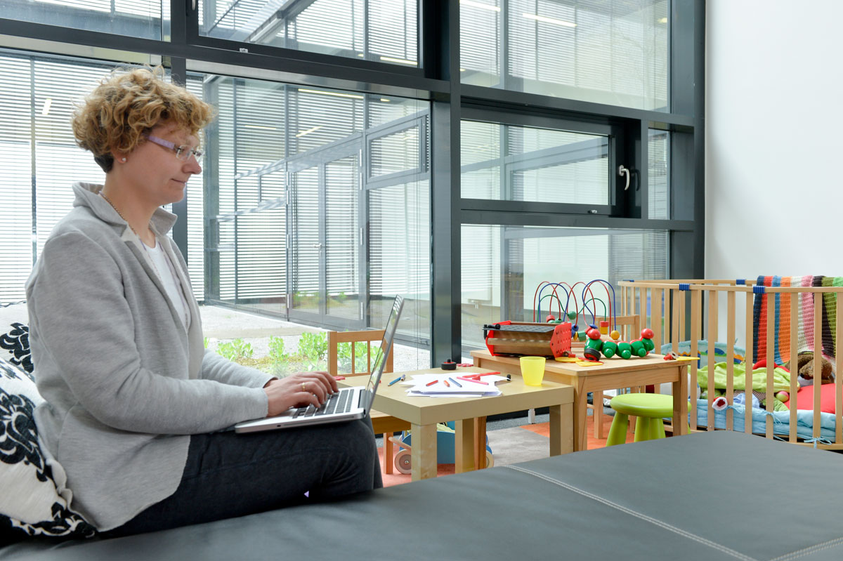 Eine Frau sitzt am Laptop und arbeitet in einem Familienzimmer