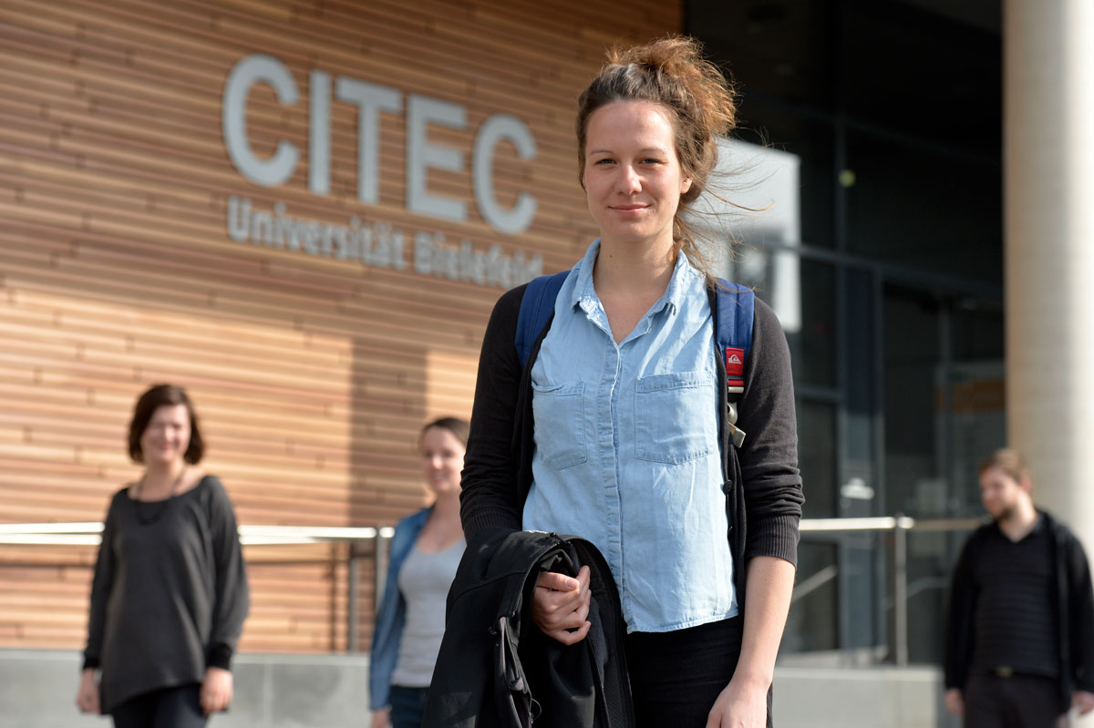 StudentinVormCITEC Eine Gruppe Student/innen in Bewegung vor einem Universitätsgebäude