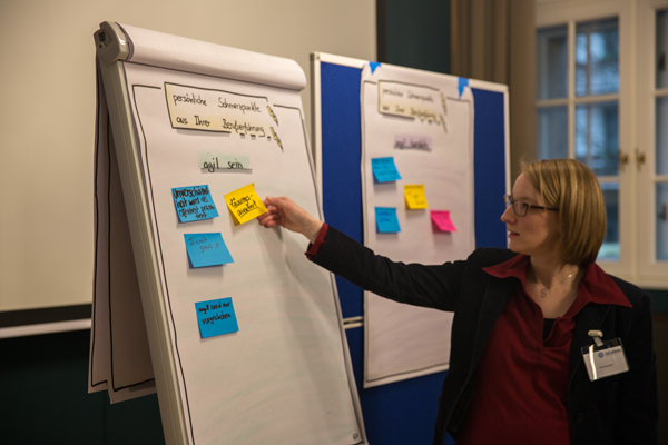 Workshopleiterin Ruth Steinseifer heftet eine Notiz an ein Flipchart