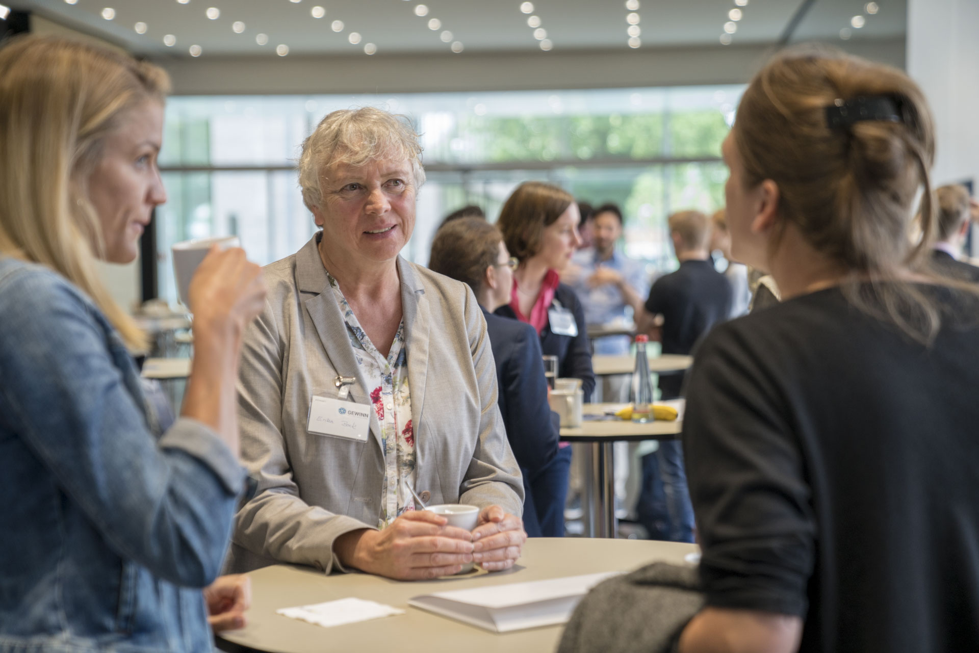 Drei Frauen diskutieren um einen Tisch herum stehend