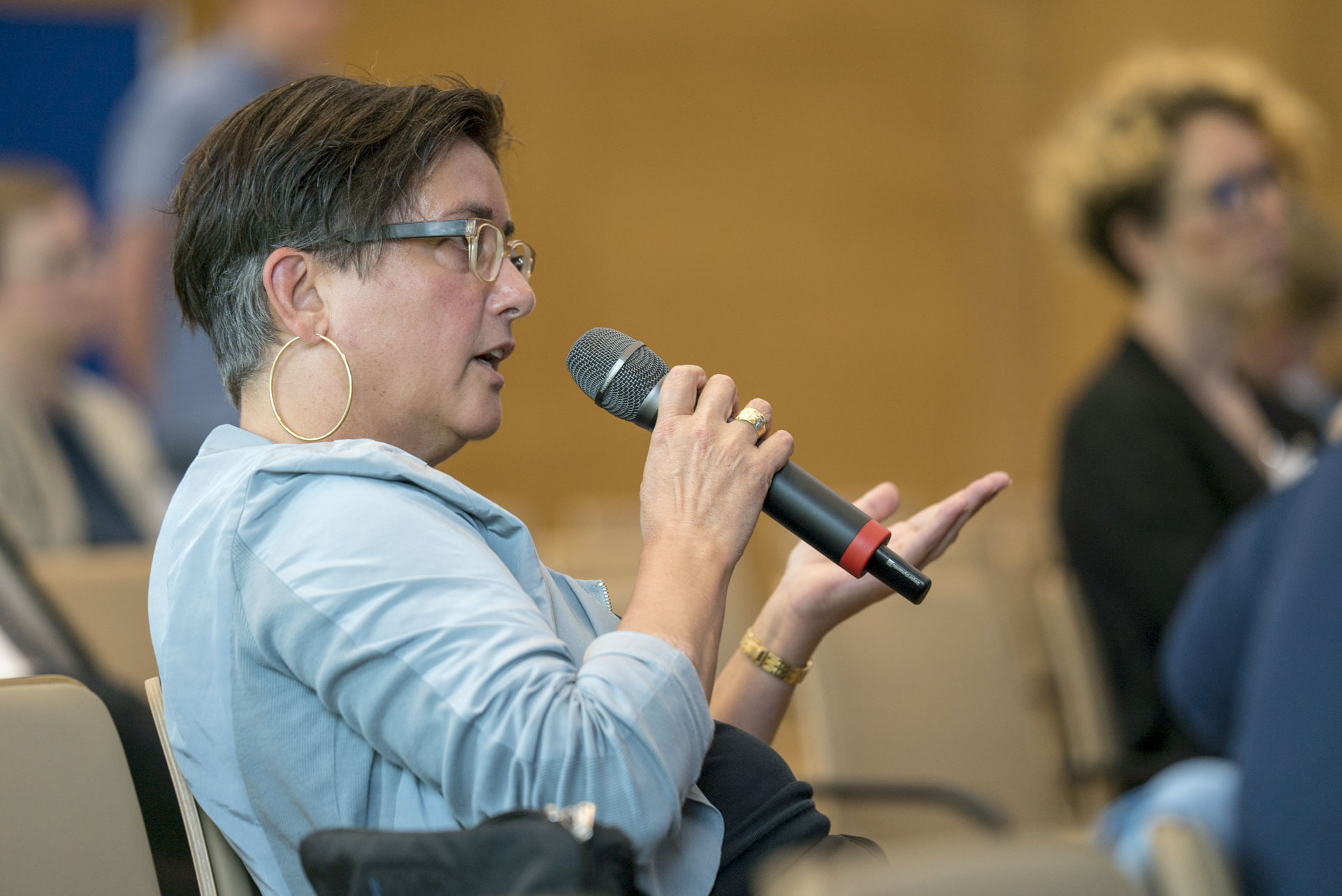 Teilnehmerin sitzend mit Mikrofon stellt eine Frage