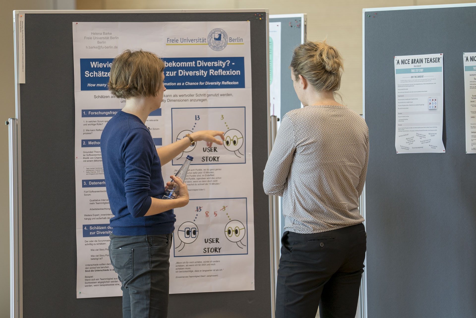 Zwei Frauen stehen vor einem Plakat und sind im Gespräch