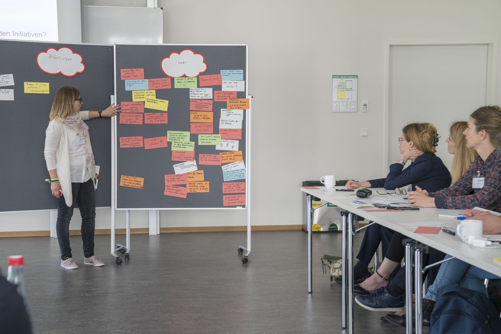 Referentin steht vor Pinnwand und erläutert die Inhalte