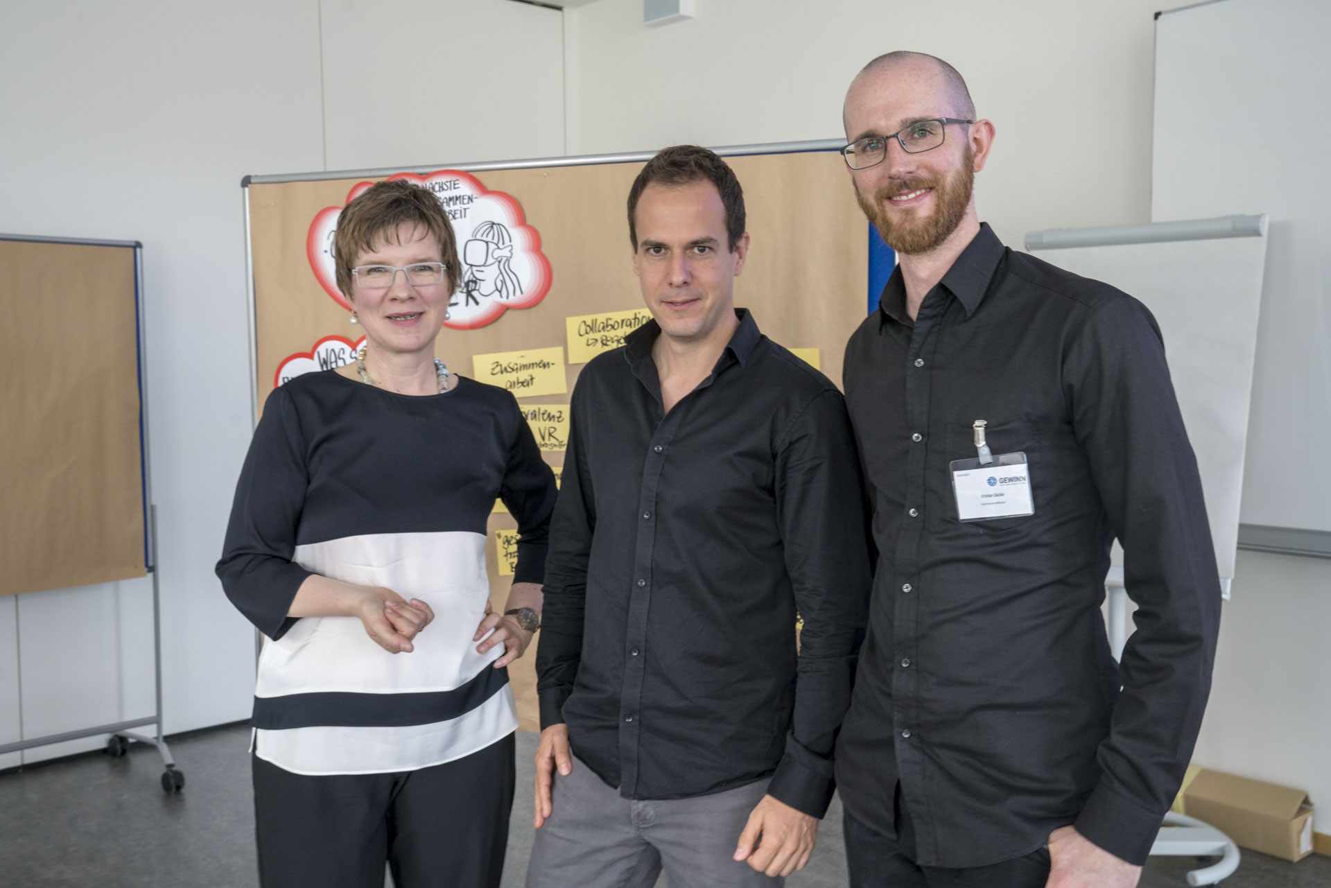 Drei Personen stehend in die Kamera schauend